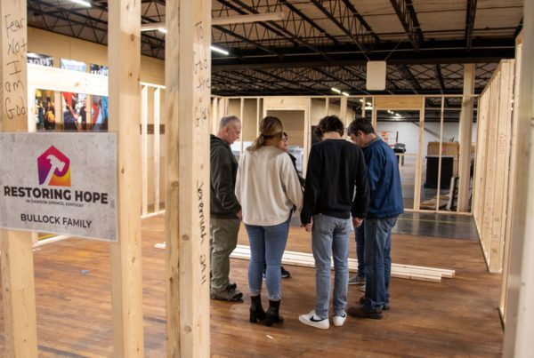 A group of five people engaged in discussion inside a spacious, industrial-style building.