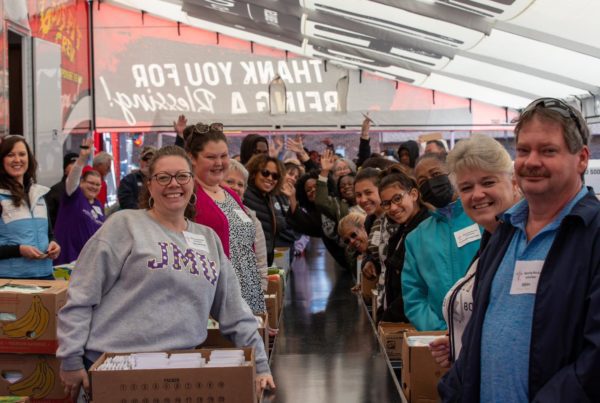 A large group smiling together in a crowded indoor setting.