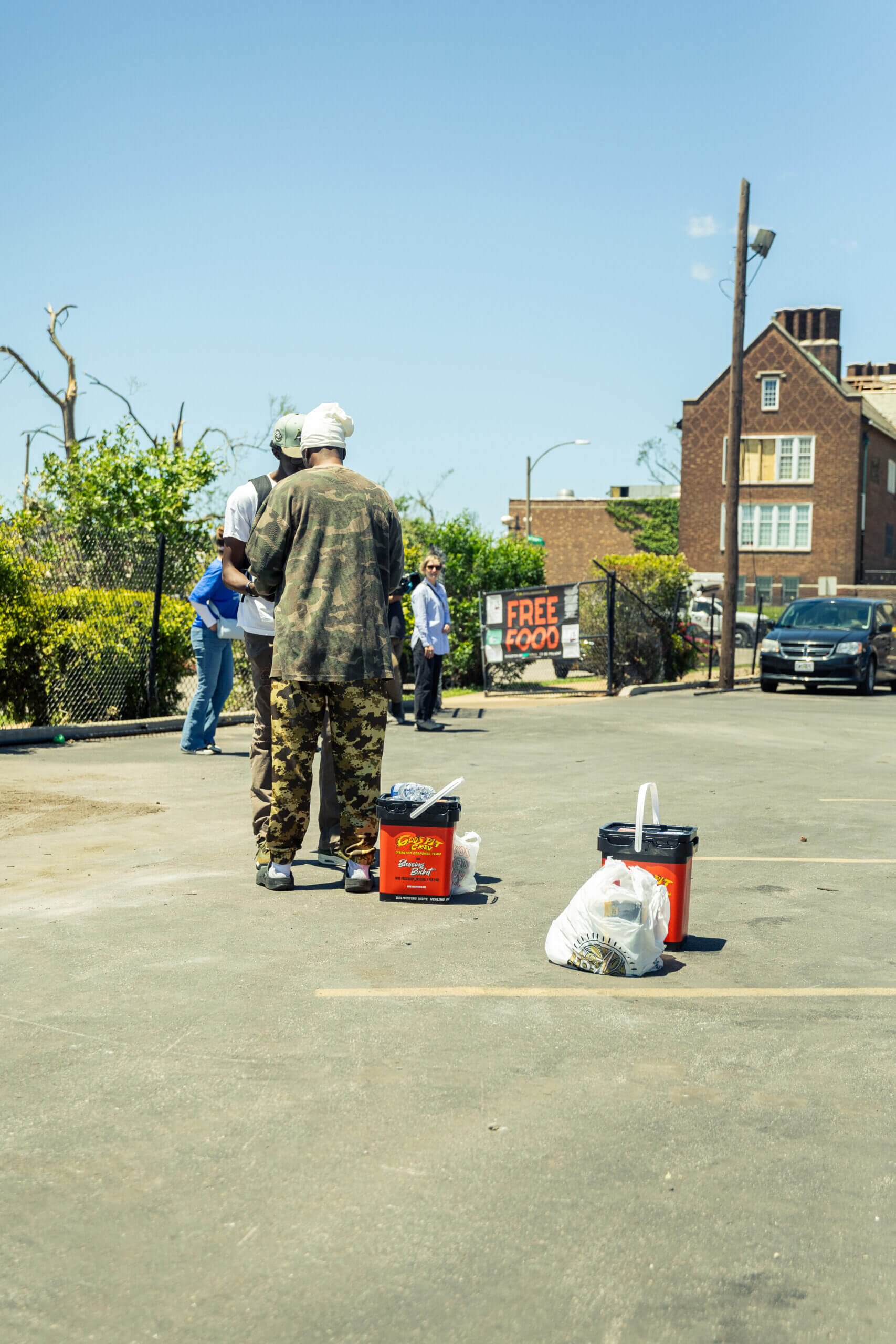 Two men standing near painting supplies on a sunny street.