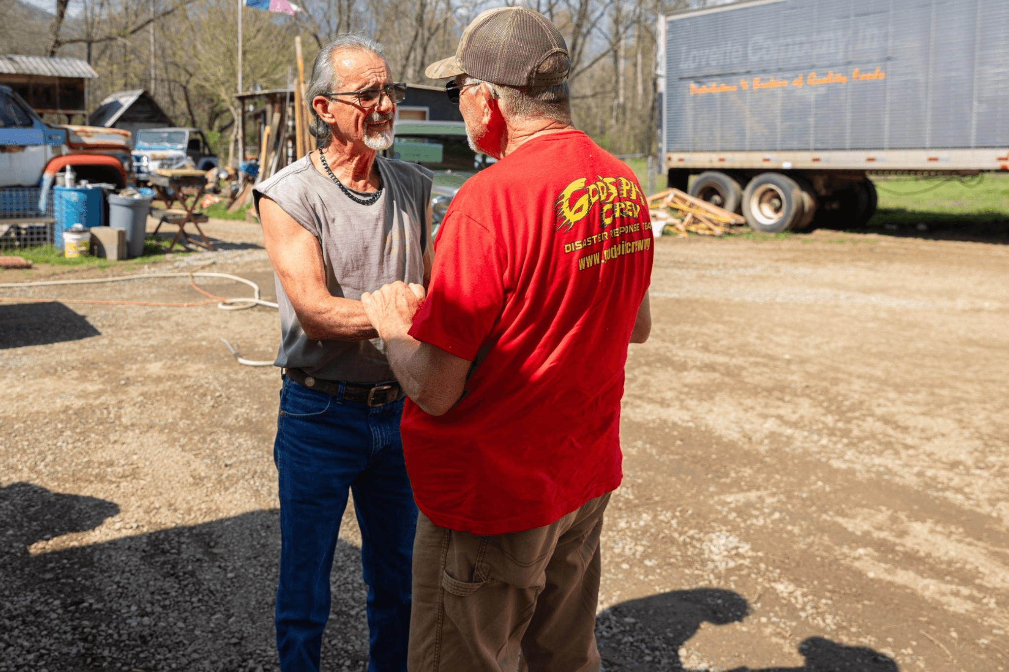 Two men shaking hands outdoors on a sunny day.