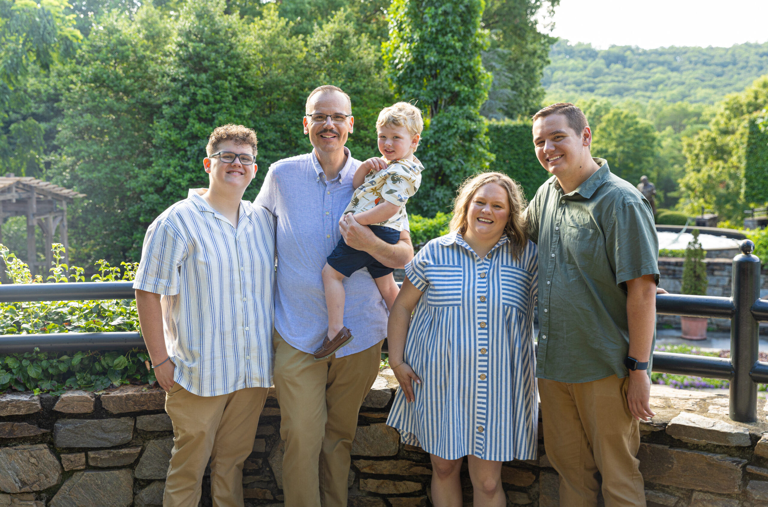 A happy family posing outdoors on a sunny day.