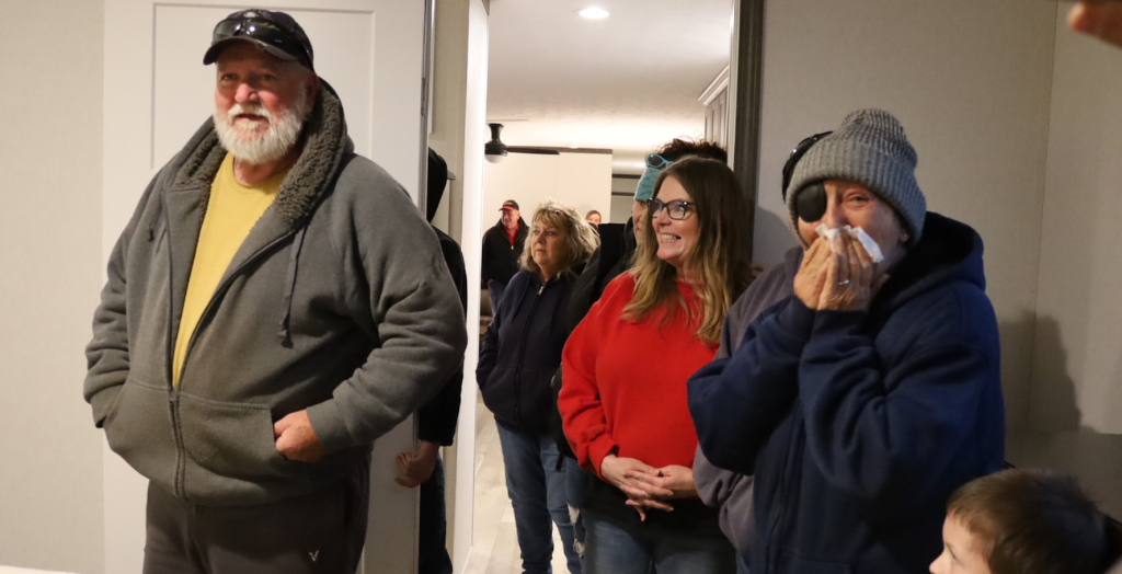 Group of people indoors, some wearing winter clothes and masks.